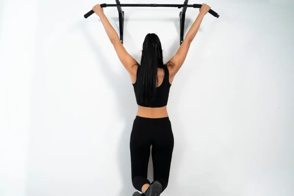 Mulher praticando barra fixa na parede, exercício essencial da calistenia.