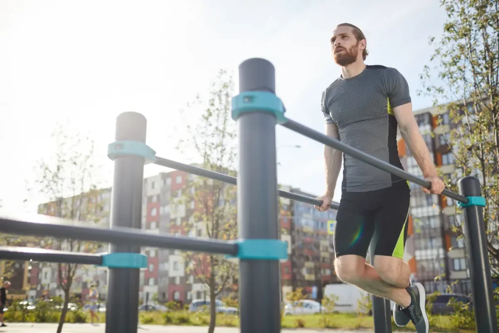 Homem fazendo barra paralela ao ar livre. Homem treinando barra paralela em um parque.