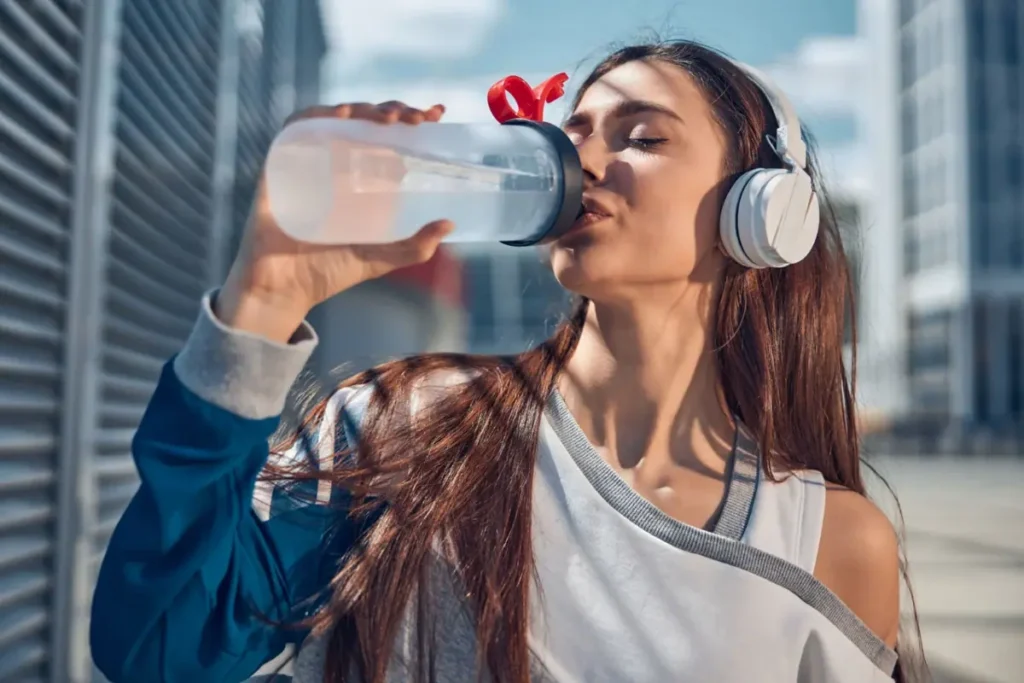 mulher segurando uma garrafa de água transparente.