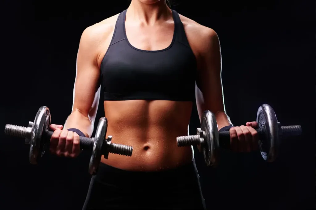 Mulher jovem de pele bronzeada com um corpo definido executando rosca direta com alteres