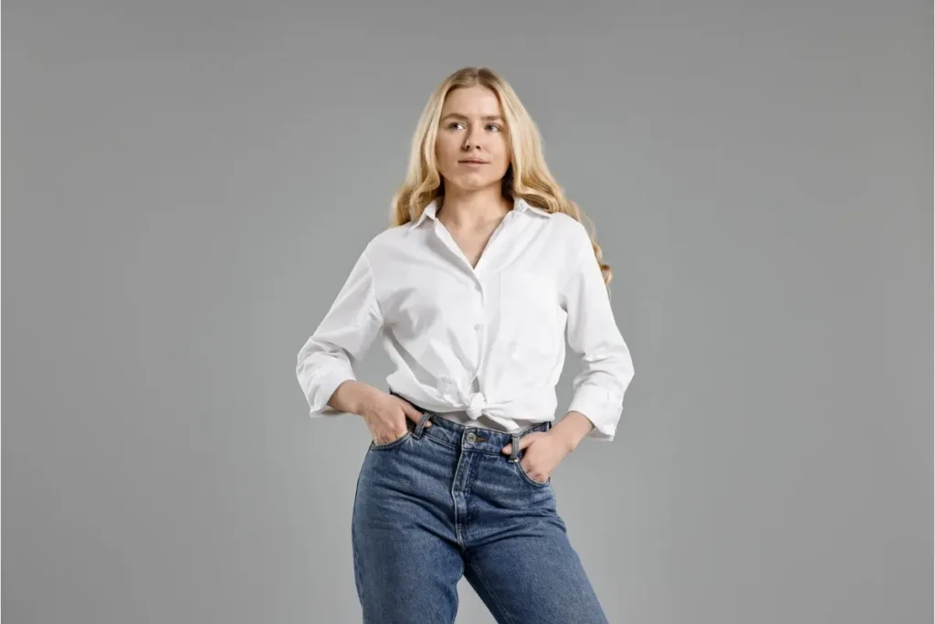 mulher loira em look casual com camisa jeans. Representa o empoderamento e a dica de vestir-se com confiança para realçar a beleza natural.